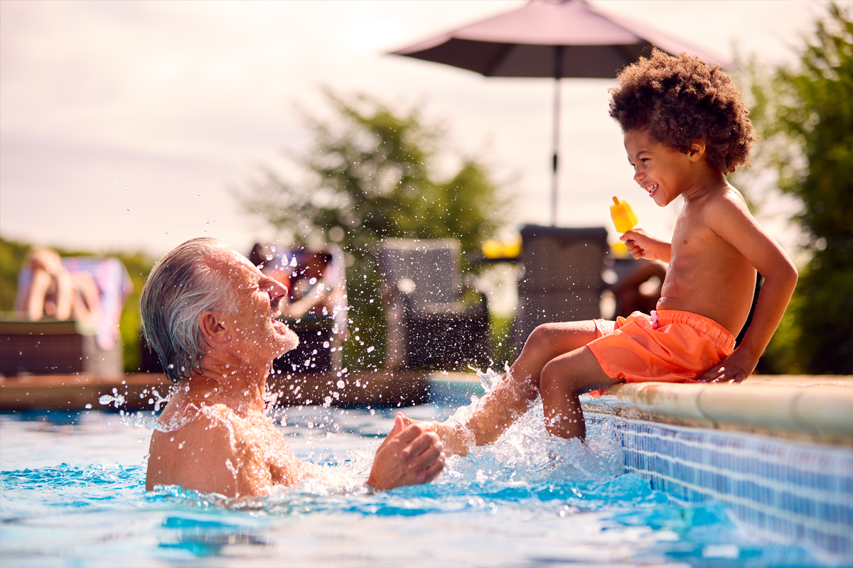 Grand-père et enfant jouant dans une piscine extérieure chauffée